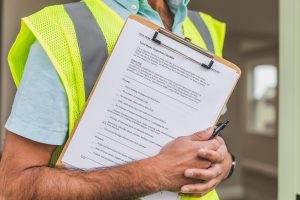 Responsable relevant une liste de contrôle sur un presse-papiers pendant une vérification de sécurité